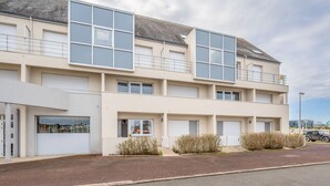Un edificio moderno de dos pisos con amplios ventanales, techo plano y un área de estacionamiento al frente.
