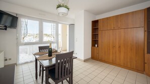 Un comedor con mesa y sillas, un armario de madera y vista al puerto deportivo a través de la ventana.