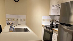 A kitchen with a stainless steel refrigerator, a microwave, an oven, and a sink. - John's Aspens Ski In/Out (Whistler)
