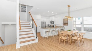 A modern kitchen with white cabinetry, a central island, and a dining area with wooden furniture.