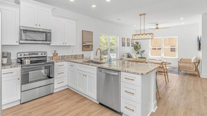 A modern kitchen with white cabinetry, stainless steel appliances, and a central island.