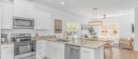 A modern kitchen with white cabinetry, stainless steel appliances, and a central island.