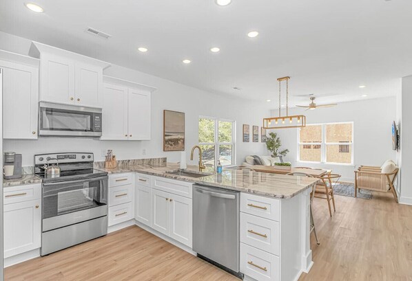 A modern kitchen with white cabinetry, stainless steel appliances, and a central island.