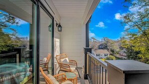 A balcony with wicker chairs and a glass door, overlooking a residential area. - 4BR Beach Oasis w/ Private Pool! 1000 ft from the water (Myrtle Beach)