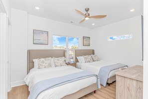 A bedroom with two beds, a ceiling fan, and large windows. - 4BR Beach Oasis w/ Private Pool! 1000 ft from the water (Myrtle Beach)