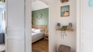 A bedroom with a bed, bedside table, and a wall-mounted shelf with decorative items. - Rêve Emeraude - 100m de la Plage (Cancale)
