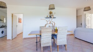 Un comedor con una mesa y sillas, una lámpara colgante y una puerta que da a otra habitación.