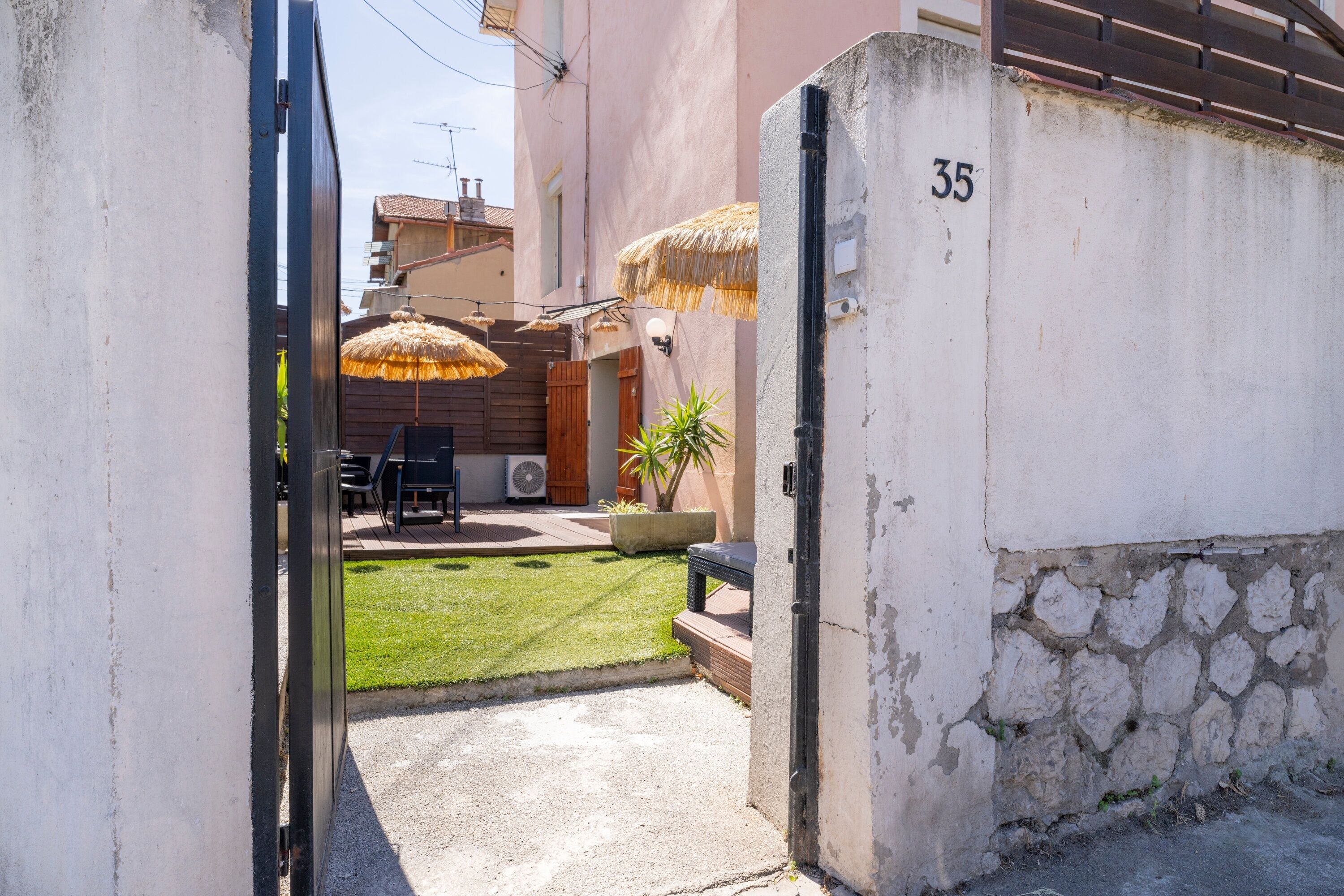 Une ruelle étroite avec une petite cour, une clôture en bois et le chiffre « 35 » peint sur un mur.