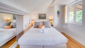 Une chambre d’hôtel moderne avec un grand lit, deux tables de chevet avec des lampes, une armoire et une grande fenêtre avec des rideaux.