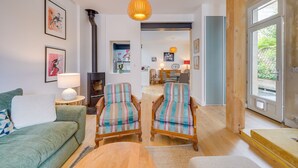 Un salon comprenant un canapé, deux fauteuils à rayures, une table basse en bois et une lampe suspendue.