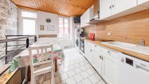 Una cocina con armarios blancos, encimera de madera, lavadora y comedor con mesa y sillas.