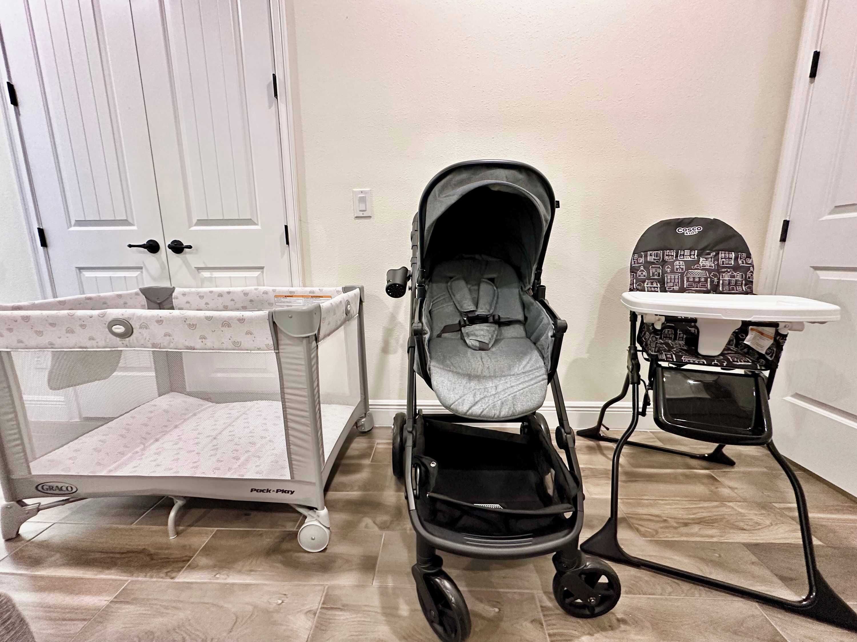 A baby play area with a Graco Pack-Play, a stroller, and a high chair.