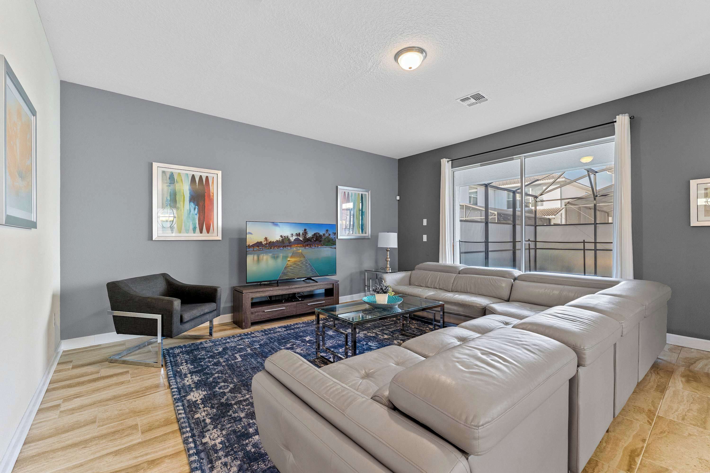 A modern living room with a sectional sofa, a flat-screen TV, and artwork on the walls.