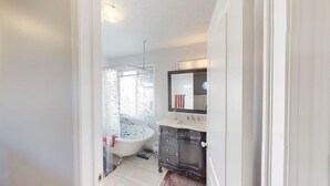 A bathroom with a bathtub, a vanity with a mirror, and a shower curtain. - Cozy&comfy family size house. Beautiful location, near COP. Pet friendly &Clean. (Calgary)