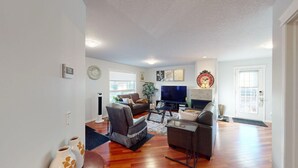 A living room with a flat-screen TV, two sofas, a coffee table, and a fireplace. - Cozy&comfy family size house. Beautiful location, near COP. Pet friendly &Clean. (Calgary)