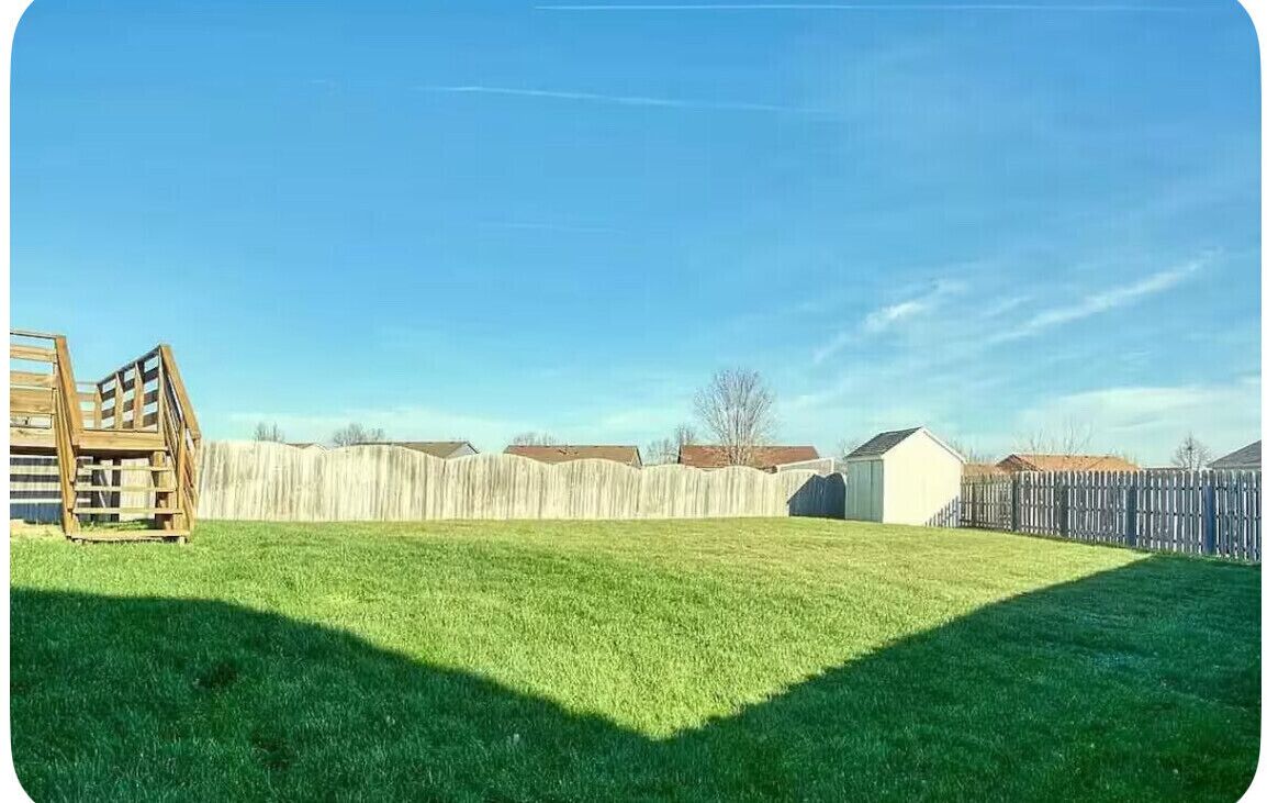 A backyard with a wooden playset, a wooden fence, and a small shed.