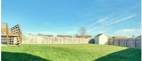 A backyard with a wooden playset, a wooden fence, and a small shed.