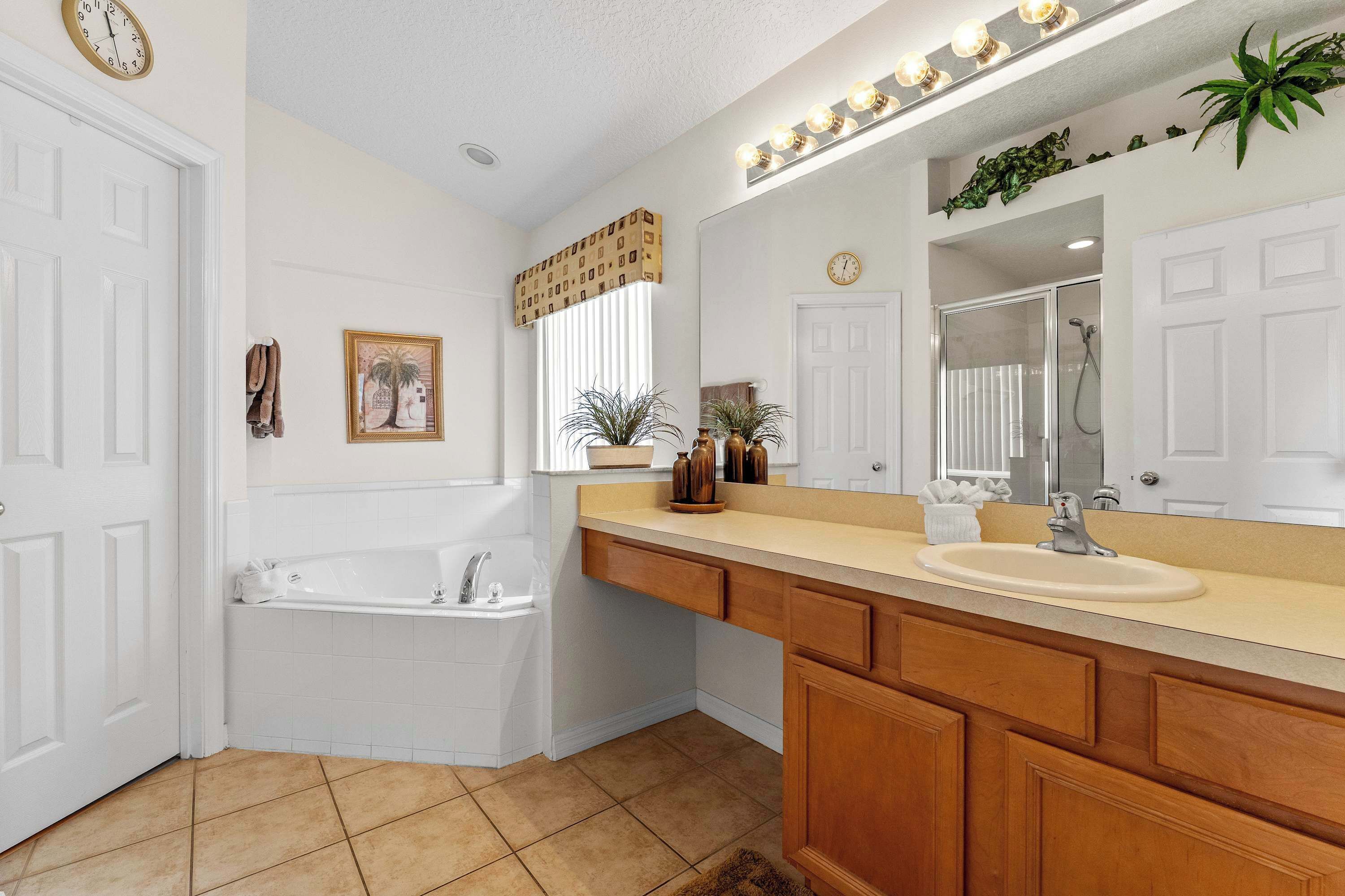 A bathroom with a bathtub, sink, vanity, and a large mirror.