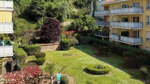 A residential building with multiple balconies and a lush garden.