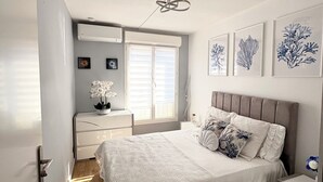A bedroom with a bed, bedside tables, a dresser, and a window with blinds.