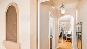 A hallway with a wooden floor, a door leading to a living room, and a window with a diamond pattern. - Rendezvous at Regal Palms - Nearby Theme Parks! (Davenport)