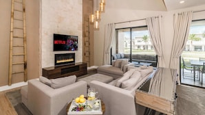 A modern living room with a fireplace, a flat-screen TV, and a large window with curtains.
