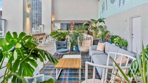 Un espace de détente moderne, doté de sièges, de plantes et d’un ventilateur de plafond.