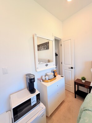 A compact room with a white minibar, a coffee maker, a small table with a plant, and a door leading to another room. - Cozy Private Room 1 Near Seattle & Mt. Rainier – Quiet & Comfy Stay + Car Rental (Bonney Lake)
