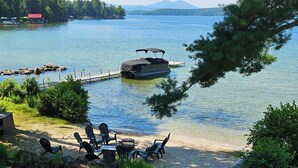 A lakeside deck with outdoor seating, a dock, and a boat.