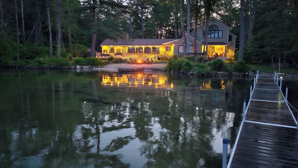 A lakeside cabin with a dock extending into the water, surrounded by trees.