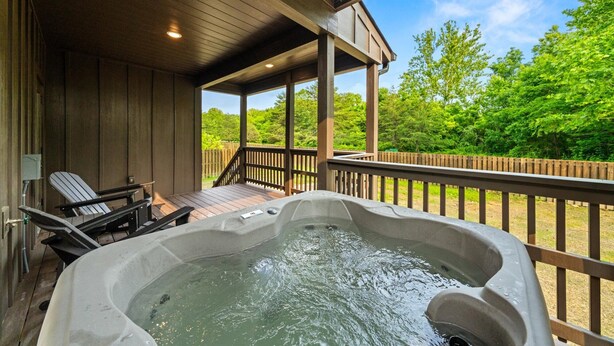 A hot tub on a wooden deck with a view of a forest.