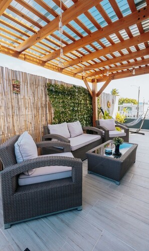 An outdoor seating area with wicker furniture, a bamboo wall, and a wooden pergola. - Charming 2-bedroom apartment in enchanting Cataño with AC, WiFi (Cataño)