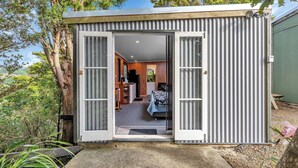 Una estructura pequeña de metal con marco, con una puerta que da a un cuarto con cama y escritorio.