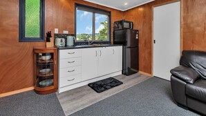 Una cocina moderna con paneles de madera, un ventanal grande, un refrigerador negro y un sofá de cuero negro.