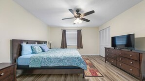 A bedroom with a bed, a TV, a ceiling fan, and a window with curtains. - Clean & Cozy 2, Near MLB Airport, HRMC, Food, Nightlife, Beaches & Shopping! (Melbourne)