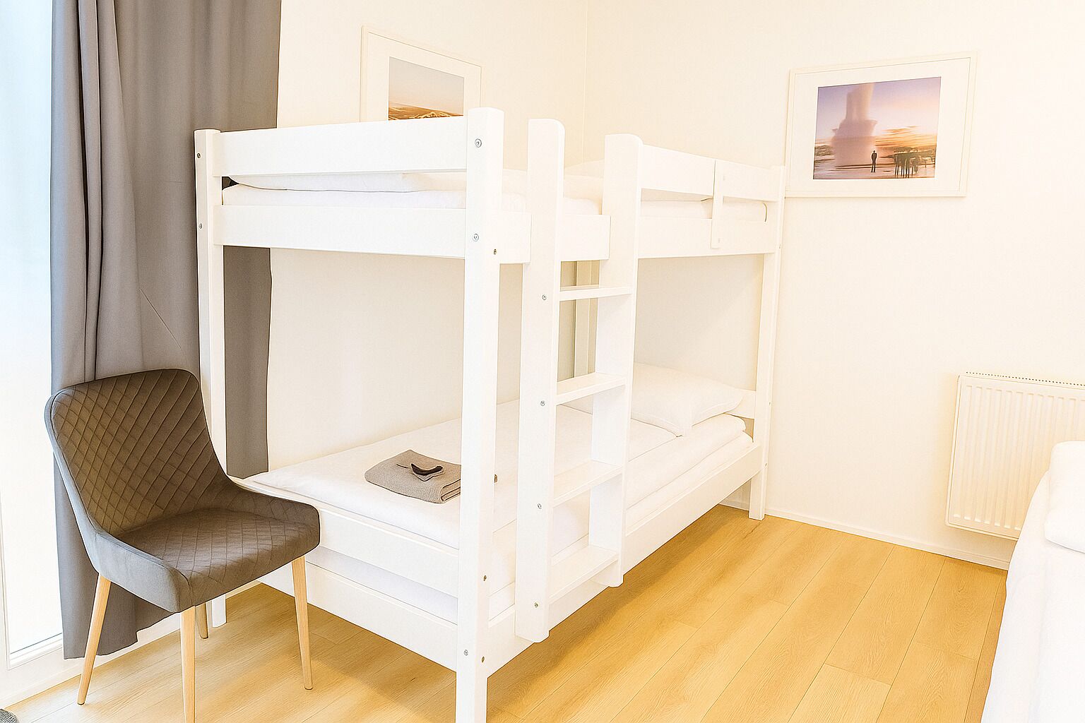 Habitación con literas, una silla y un cuadro en la pared.