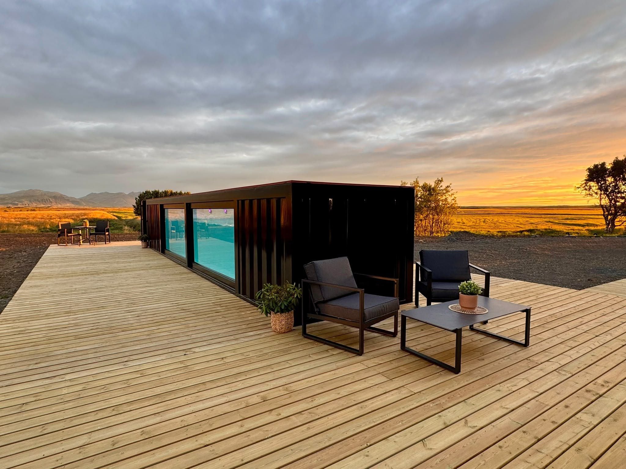 Una terraza de madera con mobiliario exterior, una piscina y vistas al paisaje.