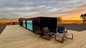 Una terraza de madera con mobiliario exterior, una piscina y vistas al paisaje.