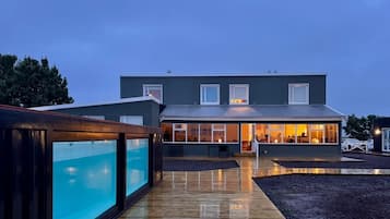 Et moderne hus med swimmingpool, overdækket terrasse og et godt oplyst interiør.