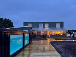 Una casa moderna con piscina, un patio cubierto y un interior bien iluminado.
