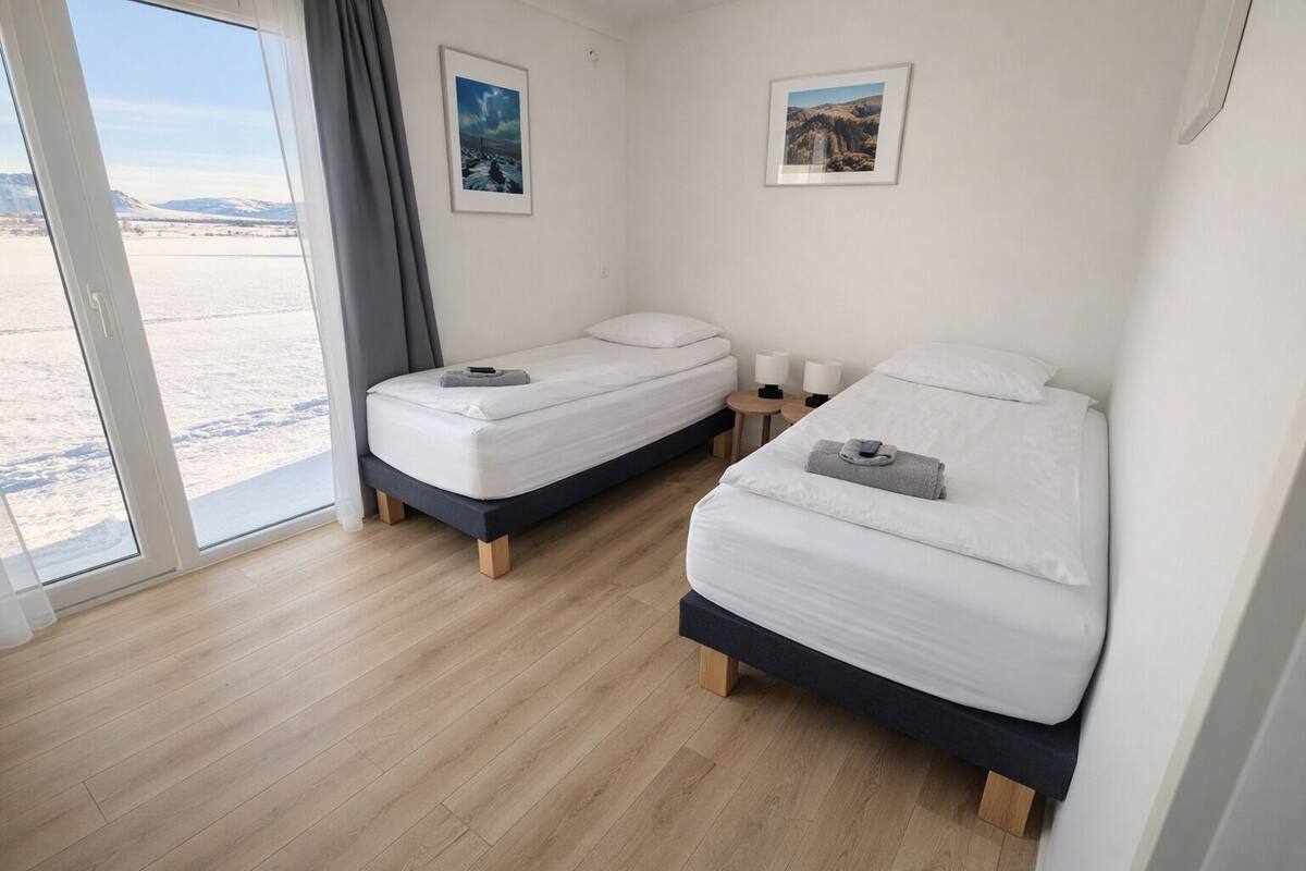 Ein Hotelzimmer mit zwei Betten, einem großen Fenster und Blick auf eine verschneite Landschaft.