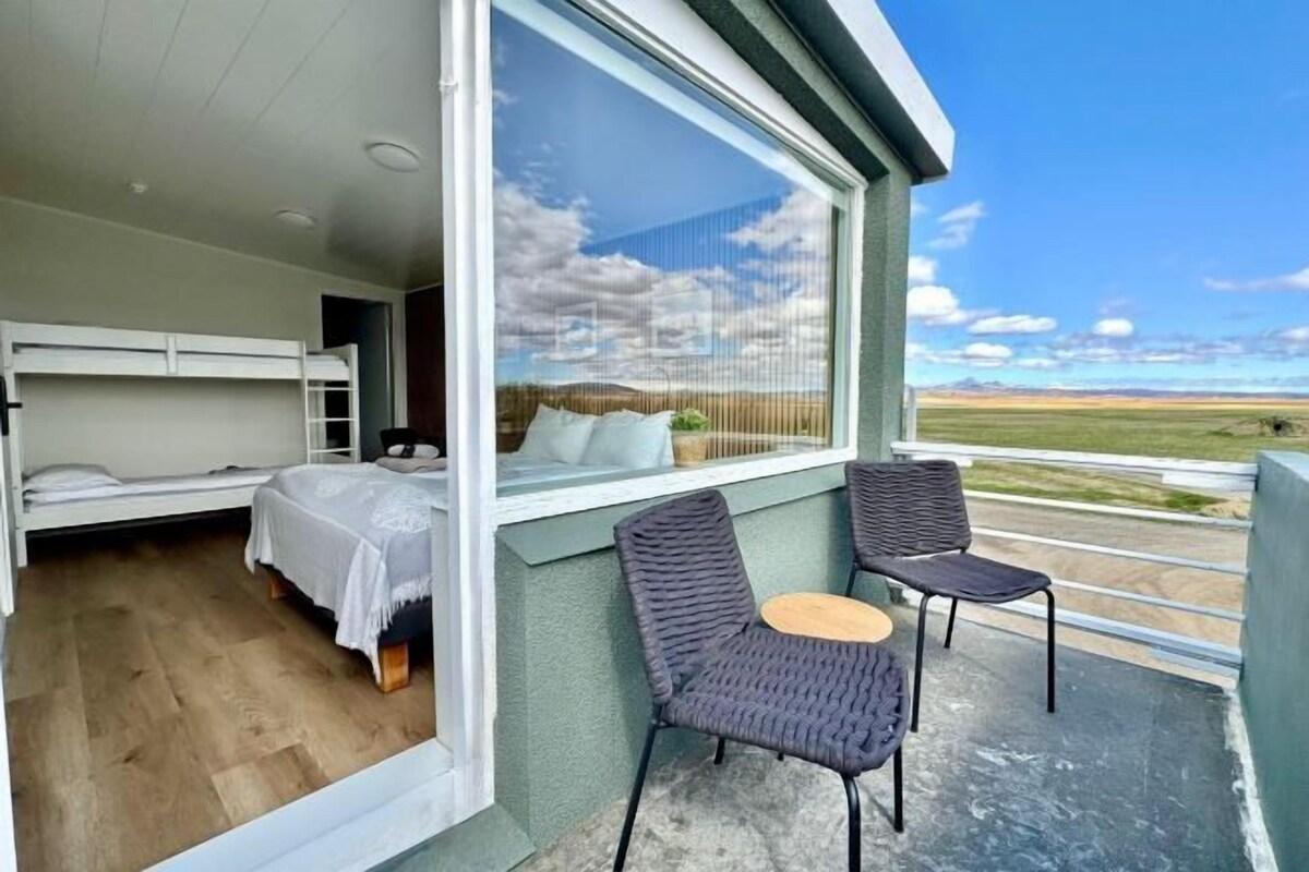 Un balcon avec deux chaises et un lit recouvert d’une courtepointe blanche.