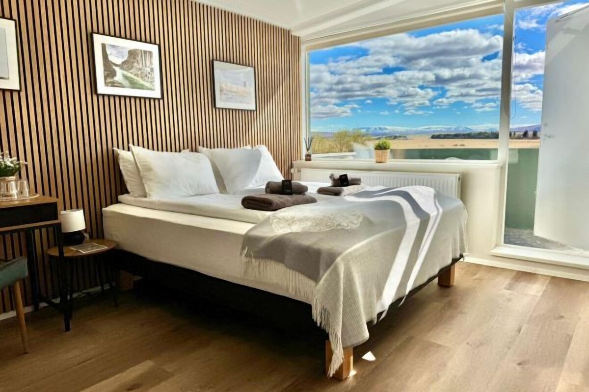 Un dormitorio con cama, escritorio y vistas al exterior.
