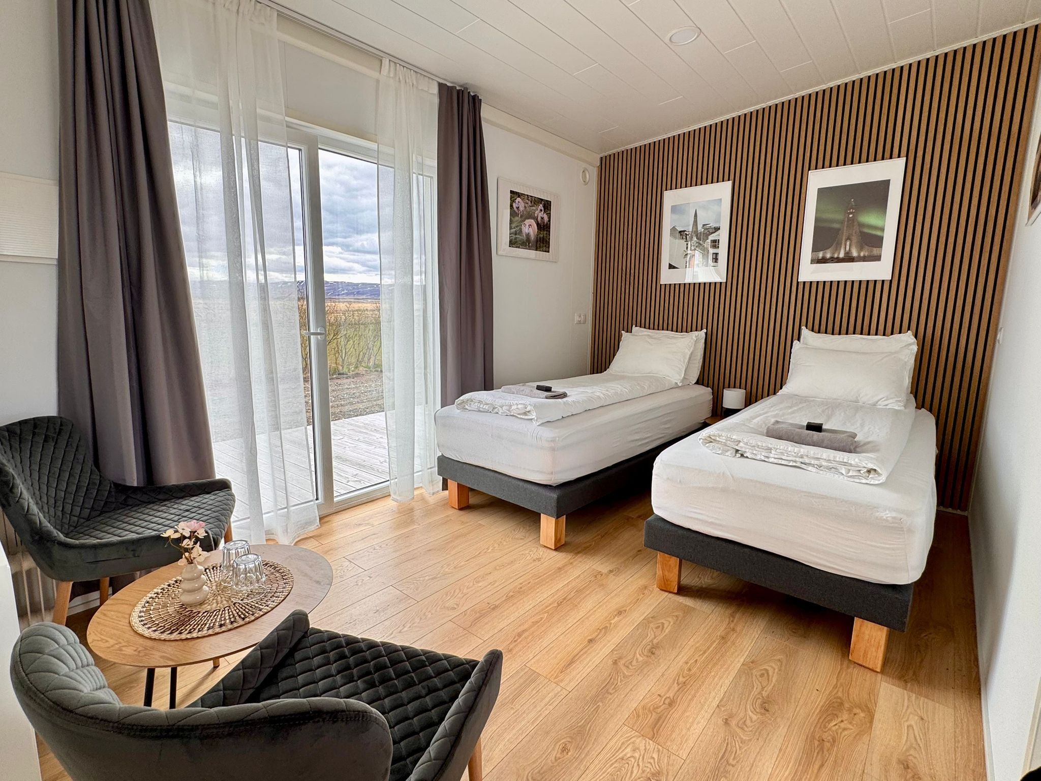 Ein Zimmer mit zwei Betten, einem Stuhl, einem Tisch und Blick ins Freie.