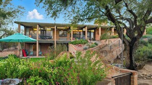 A two-story house with a covered patio, outdoor seating, and a garden with various plants and flowers. - Lazy P Ranch 12-acre retreat, spectacular mountain views, bring your horses! (Tucson)