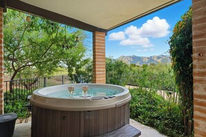 Una vasca idromassaggio con due flute di champagne su un patio con vista sulle montagne.