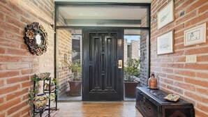 A brick-walled hallway with a wooden floor, a black door, and a small table with a decorative item. - Lazy P Ranch 12-acre retreat, spectacular mountain views, bring your horses! (Tucson)
