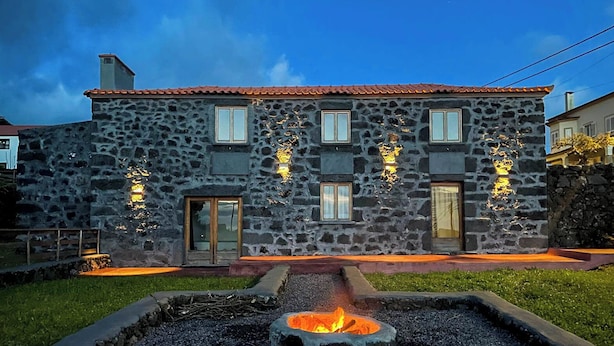A stone building with a fire pit in the front yard.