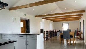 A modern kitchen with white cabinets and a wooden ceiling, leading to a dining area with a table and chairs.