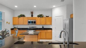 Una cocina moderna con armarios de madera, un refrigerador de acero inoxidable y una isla central con pileta.
